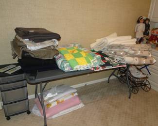 From left to right, rolling plastic storage organizer, wool blankets, some outstanding made quilts, twin comforters, and some random, under the table blankets too