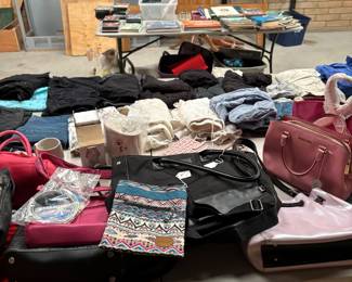 Table of Assorted Clothing, Accessories, and Books:
A collection of women's clothing, stylish handbags, accessories, and an assortment of books and DVDs. Ideal for shoppers looking for unique finds at bargain prices.