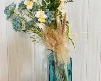 Blue glass vase with faux flower arrangement