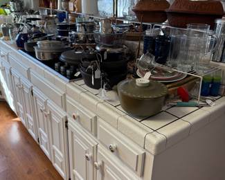 Lots of kitchen gadgets, cast iron pans and other pieces, glassware and plates