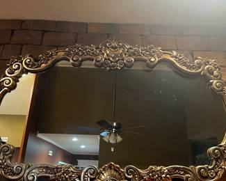 Large mirror with gorgeous detailing over fireplace.