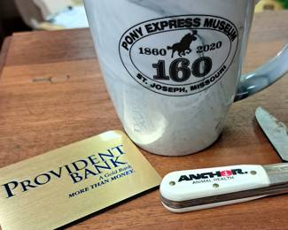 "Anchor Animal Health" knife, "Provident Bank" and "Pony Express Museum 160 Yr." mug