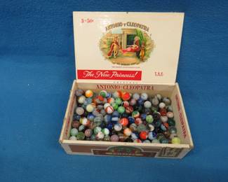 Lot 381. Marbles in an old cigar box including one that slipped past quality control