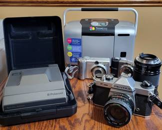 Vintage and modern cameras Including 2 cannon cameras , a pentax k1000 and a vintage polaroid.