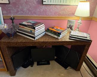 Wicker Woven Sofa Table, Books, Lamps. Below Sofa are 3 Computer Monitors.