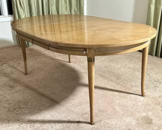 Mid-century Extension Dining Table | MCM / Mid-century modern extending dining table with three leaves, pictured with two leaves in, having a round to oval top, over splayed, taping legs with brass mounts; each leaf w. 12 in. - h. 29.25 x w. 46 x l. 70.25 in (with two leaves, as pictured)