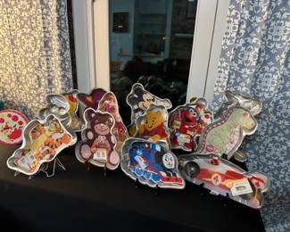 A dozen Wilton cake pans in various children's motifs. Also, the most adorable musical cake plate that turns!