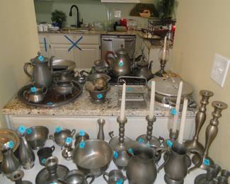 Pewter sets, pewter candlesticks, pewter pieces, pewter jugs, pewter bowl, and a bright blue X tape in the background
