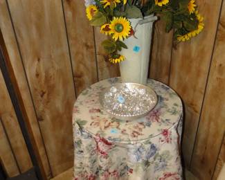 Small round table with glass top, and bowl of beads, and a large vase with sunflowers
