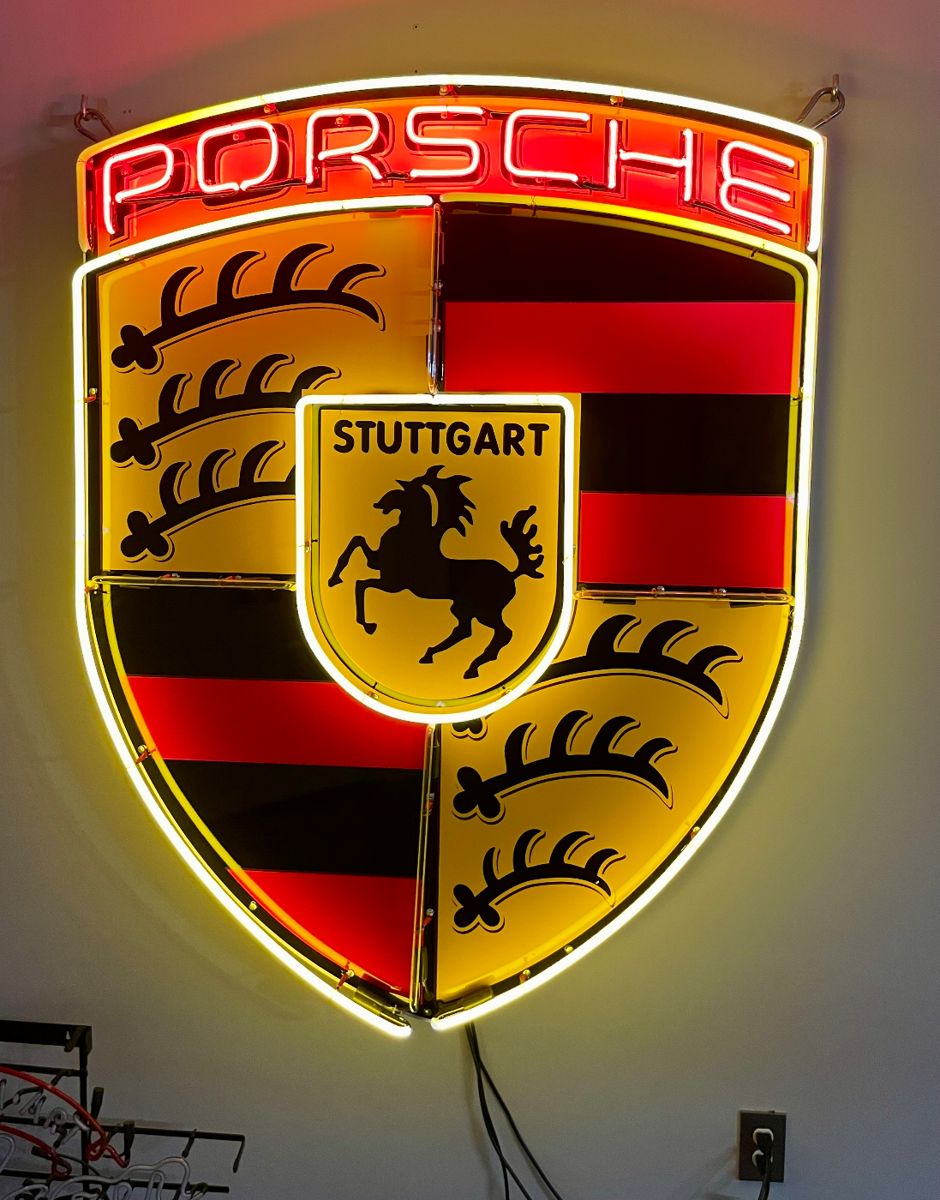Illuminated Neon Porsche Crest (44" x 36" x 8").  With vibrant gold, white, and red neon, the Porsche logo is a combination of the Stuttgart coat of arms, which features a leaping horse, and the state coat of arms of Wurtemberg, established in 1933.