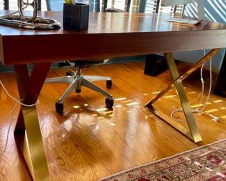 Jonathan Adler Channing Walnut and Brass Writing Desk.  Transform your workspace with the exquisite Jonathan Adler Channing Walnut and Brass Writing Desk. This piece seamlessly blends mid-century modern design with contemporary flair, featuring a  rich walnut finish that exudes warmth and sophistication. The sleek brass Neo-Classical brass crisscrossed legs add a touch of glamour, creating a visually striking focal point in any room.