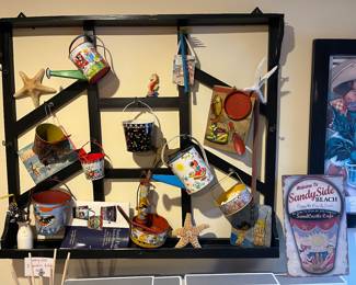 Vintage Italian kitchen rack; collection of vintage metal sand pails and watering pails; additional beach-themed decor.