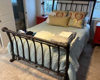 Modern queen-size bed with ornate metal head- and footboard, mattress and boxspring.