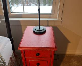 One of two matching chabby chic three-drawer nightstands painted red; one of two matching table lamps.