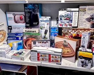 TABLE FULL OF NEW ITEMS IN BOXES