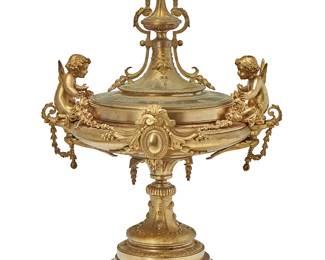 1363
19th century
A French gilt-bronze and red marble covered center bowl
The bowl mounted with opposed putti, each clutching floral garlands, alternated with opposed roundel panels with foliate motifs to each side, the lid conformingly decorated with foliate accents, raised on an architectural round base set on rouge marble, with liner
Overall: 15.5" H x 11.25" W x 9" D
Estimate: $400 - $600
