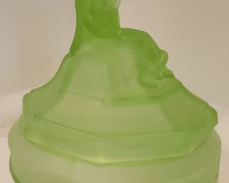 $50 OUR PRICE
L.E. Smith Green Satin Minstrel Powder Jar Another
CIRCA: 1920s/ 1930s
MEASUREMENT: 5" H. - 4 1/2" W.
CONDITION: We are offering for sale a really pretty L.E. Smith Minstrel powder jar in green satin. This pretty powder box is in Undamaged Condition without chips, cracks, or mold damage. The powder jar is clean both inside and out. The satin finish was well done. This lovely jar was made circa the 1930s.
"Minstrel" Powder Jar: The finial of this powder jar is a minstrel in the sitting position playing a mandolin. This is an L. E. Smith powder jar. There are two different shapes of lids used with this jar. The one style has an octagonal lid, while the other has a round lid. The base has a recessed horizontal band in the center section intersected by four evenly spaced recessed vertical panels. The "Minstrel" jar has been found in crystal, crystal with flashed colors, green satin, green transparent, pink satin and pink transparent.