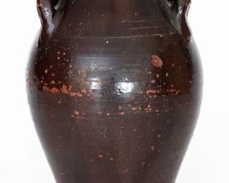 Glazed Redware Jar, Eastern TN origin, second or third quarter 19th century, ovoid jar with tooled shoulder, open loop handles, and semi-rounded rim, the surface covered in an opaque brown lead-and-manganese glaze. Heavy chipping to base. In-the-firing bubbling to glaze, primarily on one side. Exfoliation to body of jar. A 3/4" ping to one side of jar. A small amount of in-the-firing glaze spalling and/or exfoliation to handles. Top of rim with a shallow 2" flake and two chip. Reddish varnish-like substance to base and rim. H 15". ($400-$600)
