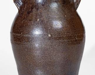 Glazed Redware Jar, Eastern TN origin, second or third quarter 19th century, ovoid jar with footed base and tall collar with angled rim molding, the handles formed from distinctive tooled clay straps with depressed centers. Surface covered in a mottled brown lead-and-manganese glaze. A 1 1/8" rim chip. A 4" hairline from rim. Shallow chipping to one handle. Light chipping to opposing handle. Surface wear around midsection. Traces of old gold paint to rim area. H 10". ($300-$500)
