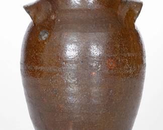 Unusual Lead-Glazed Stoneware Jar, Eastern TN origin, second or third quarter 19th century, ovoid jar with tall collar, flattened rim, and arched lug handles, the lead-glazed surface featuring olive coloration with manganese accents and orange spotting. This jar appears to be an example of lead-glazed redware fired to a stoneware temperature, resulting a vitrified, gray-colored clay body. Chips and heavy wear to rim. A chip and wear to one handle. Two chips to opposing handle. Surface wear. An in-the-firing contact mark to shoulder. H 9 1/4". ($150-$250)
