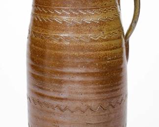 Salt-Glazed Stoneware Churn, Middle TN origin, second half 19th century, semi-ovoid churn with flared rim and ribbed strap handle, decorated with straight and wavy incised lines to the shoulder and two rows of wavy lines near the base. A 1 1/2" x 2 1/2" reglued wedge at rim and a 5 5/8" x 6" reglued section descending from rim, including some coloring along the break of the smaller wedge and chipping along the larger break. A chip and in-the-firing contact mark to handle. A large inverted T-shaped crack to base area, extending onto underside where it has been colored. H 14 5/8". ($150-$250)
