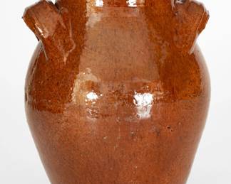 Glazed Redware Jar, Eastern TN, second or third quarter 19th century, ovoid jar with footed base, flaring rim, and wide horizontal strap handles with raised banding, the exterior and interior surface covered in a heavy lead glaze colored with manganese or iron. Provenance: Previously purchased at a Salisbury, NC estate auction. Purchased by Wahler from Steve Compton in 2002. Chipping to handles. A 1/2" rim chip and other minor rim chips. Surface wear around midsection. Foot with two small chips and two miniscule nicks. H 8 3/4". ($500-$800)
