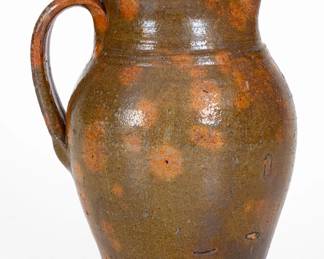 Glazed Redware Pitcher, TN origin, probably Sullivan County, circa 1840-1880, ovoid pitcher with flared collar and heavily-ribbed handle, the lead-glazed surface featuring colorful mottling in shades of olive and brown with orange spotting. In her notes, Wahler states, "Terminal looks like the pitchers which I have come to associate with LMH [Lewis Manning Haun]." Provenance: Found in Bristol and originally purchased by Mary Jo Case. Wear to handle and rim. Light surface wear. H 9 5/8". ($400-$600)
