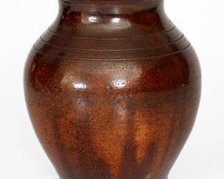Glazed Redware Jar, Greene County, TN origin, possibly Christopher Alexander Haun, circa 1840-1860, finely-potted, ovoid jar with footed base, tooled shoulder, and tall collar with thin, semi-rounded rim, the exterior covered in a mottled brown lead-and-manganese glaze, the interior covered in a clear lead glaze over a yellowish ground. Very nice condition with a few minor nicks to rim, a minor base chip, and some light surface including a minor surface chip to midsection. H 8 5/8". ($500-$800)
