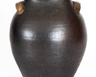 Glazed Redware Jar, Carter County, TN origin, circa 1820-1840, ovoid jar with tooled shoulder, tall collar with semi-rounded rim, and ribbed strap handles with depressed terminals, the surface covered in a black lead-and-manganese glaze. Old gold paint to handles and rim. Provenance: Originally found in Carter County, TN. Some light, scattered glaze wear to body. Rim is out of round. A small chip to one handle. A few small chips to interior of rim. Some faintly-glazed areas to jar, as-made. A faint 4 1/2" Y-shaped hairline to underside, forming a vertical 7" hairline ascending base below one handle. A few minor in-the-firing pings to surface. Minor traces of old green paint to surface. A few very short, faint vertical lines at base, not visible on interior. Interior with scratches and some small flakes. H 13 1/2". ($200-$300)
