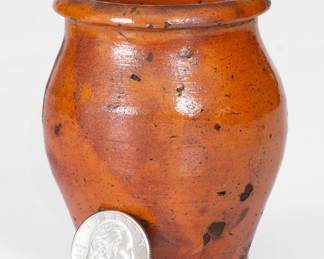 Scarce Miniature Glazed Redware Jar, TN origin, possibly Hawkins County, circa 1800-1840, ovoid jar with footed base and semi-rounded rim, the surface covered in a streaky lead glaze producing glossy, bright-orange coloration over a matte red ground. Exfoliation to interior. A 1 1/4" hairline from rim. Some surface flakes to exterior. Some extremely minor rim wear. H 3 1/4". ($200-$400)
