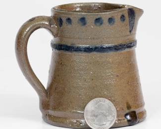 Rare Miniature Cobalt-Decorated Stoneware Pitcher, attributed to the Decker Pottery, Washington County, TN, circa 1872-1910, tapering pitcher with footed base and raised molding to shoulder, decorated with cobalt spots and accents to the collar and a band of cobalt to the molding below. Exhibited: Made in East Tennessee: Pottery, Museum of East Tennessee History, 1996; Tennessee Turned, Earthenware and Stoneware Made in East Tennessee 1800-1900, Museum of East Tennessee History, May 16-October 30, 2011. Literature: Illustrated in Wahler, Tennessee Turned, Earthenware and Stoneware Made in East Tennessee 1800-1900, p. 156, 176, 221, and 233. Very nice condition with a few small spout chips, a small chip to interior of rim, and a small chip to underside along bottom edge. H 3 1/2". ($800-$1200)
