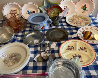 Many children’s dishes, tin, stainless, pewter, ceramic, plastic and glass. Includes two Dione Quint bowls. 