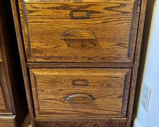 Oak two drawer file cabinet, accommodates legal sized documents and folders.