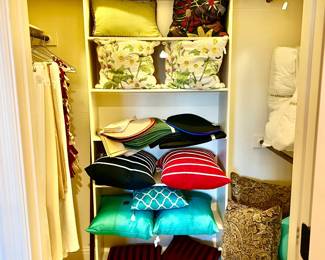 LINEN CLOSET WITH PRETTY PILLOWS AND TABLECLOTHS.