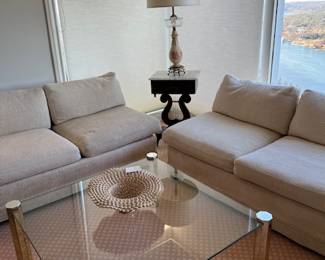 Two matching white sofas and glass and brass coffee table