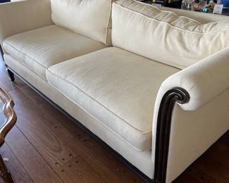 One of two matching beige sofas with wood enhancements