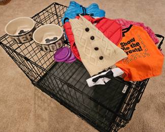 Small dog crate with various coats and sweaters