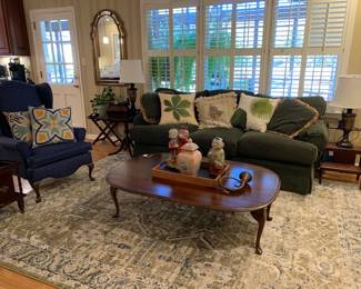 Green sofa, dropleaf coffee table, area rug, navy wingback chair