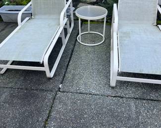 Pair of Brown Jordan chaises. 76"l when flat by 26"w. Round table between them is 18" diameter x 18"h. As found. Available during in-person shopping hours only.