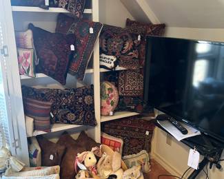 Gorgeous needlepoint, tapestry, and hide pillows.  Basket of stuffed bunnies. Samsung TV on stand. 