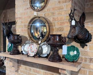 Vintage convex mirrors, carved Black Forest wood mounts, Majolica plates (green), antique pewter plates, Davenport porcelain plate (center), pair of resin hunting urns