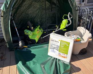 Here is the green Tidy Tent Storage system with zippers with the flap down,  in the center, you can see the Earthwise 40 V lithium 22 inch wide snowblower, a gray two wheel yard cart, a 20 inch heatedbird bath, look closely inside and you can see one of the two wheel dolly(s) for sale.