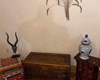 plant stands on the left, heavily carved chest, on the rith is an oriental multi drawer end table and a few of the interior decorations