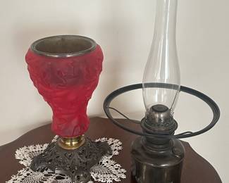 Lot 200 Red Satin Kerosene Parlor Lamp.  Fenton?  Beautiful red satin glass with leaf pattern, iron base.  Insert separates from base to light the way to bed at end of evening.  It is original, not converted to electric. Lamp measurements 27”h to top of clear chimney.  There is a crack in the shade at the top, see photos.   Beautiful lamp!