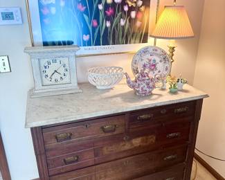 Antique cabinet with marble top and multiple drawers.