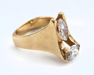 An 18k Gold and Diamond Modernist ring custom made by Cary Stefani, Birmingham, MI.  Features two marquis cut Diamonds, half bezel set vertically and horizontally, each approx. 10 x 5 1/2 mm, estimated 1.9-2.0 cttw, on a wide band with squared bottom.  Marked "18k" and "Stefani".  13.2 grams total.  Approx. 1 1/2mm chip to underside edge of horizontal Diamond, tiny chip to outer point of vertical Diamond, some surface wear.  Size 5 1/4.