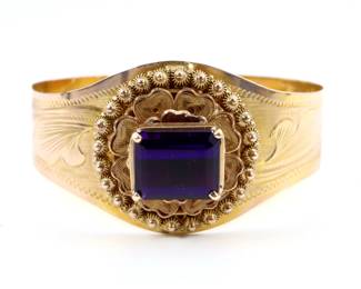 A Victorian 9k Gold and Amethyst bracelet.  Features an Emerald cut prong set Amethyst, approx. 10.5 x 13 mm, on a filigree mount with engraved band and adjustable clasp.  18.9 grams total.  Some distortion to clasp.  6 1/4" interior diameter at loosest setting.