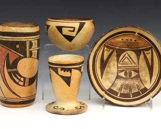Four pieces of 20th century Native American Earthenware, likely Hopi.  Includes a cylinder form vase, a foot vase, a low bowl and a small bowl with geometric polychrome decoration.  Low Bowl and footed vase with hairlines, some wear to decoration and flakes.  Up to 6 1/2" diameter and 6 1/2" high.  
