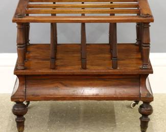 A 19th century English canterbury.  Mahogany construction with an open framework upper section for magazine storage over a molded base with a drawer on turned legs and casters.  Old refinishing with some wear, repairs and damage, loose bottom board and legs.  20 1/2 x 14 3/4 x 18 3/4" high overall.