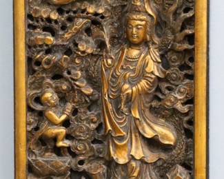 A Chinese Gilded carved wooden panel of Guan Yin.  Depicted standing on a Dragon with birds, fruit and acolyte.  Some wear to original Gilded finish, minor shrinkage and damage.  12 x 21" high overall. 